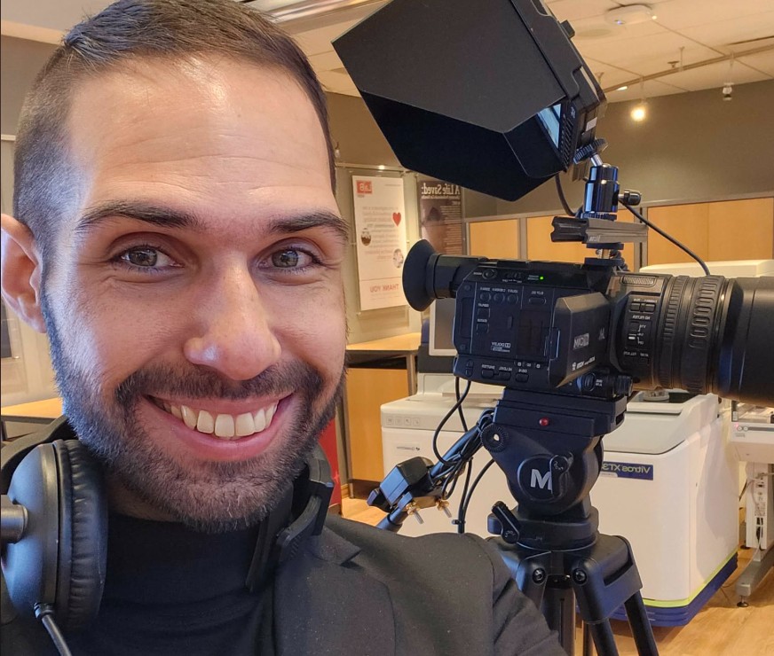 Livestream Cmera Operator smiling with a camera in the rain.